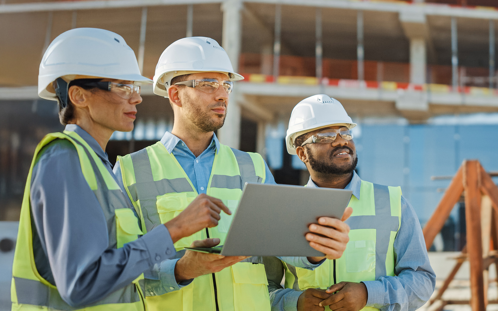 Diverse Team of Specialists Use Laptop on Construction Site Diverse Team Of Specialists Use Laptop On Construction Site