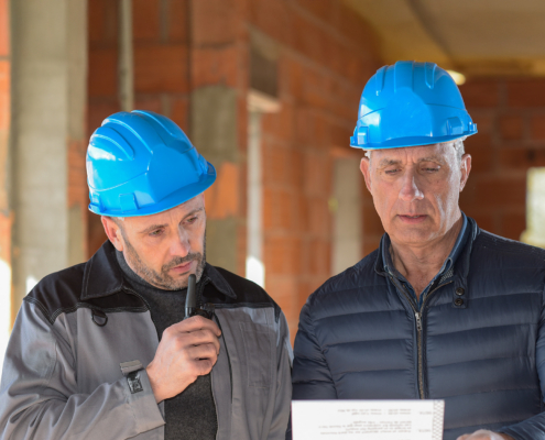 Architect And Contractor Looking At Plans On A Building