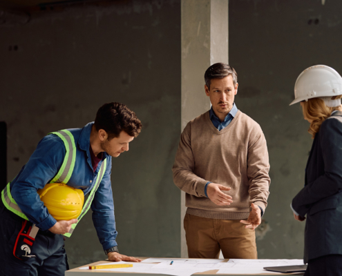 Building Contractor Talking About Project Plans With His Team At Construction Site