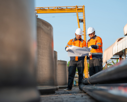 Construction Engineer And Supervisor Checking Blueprint For Heavy Steel Pipeline